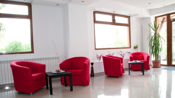 A modern room with three red chairs and a small table, large windows, and a potted plant. - Otopeni (Otopeni)