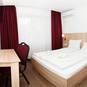 Una habitación de hotel con una cama de madera, un escritorio, una silla y una mesita de noche con lámpara.