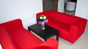 A red sofa set with a small table and a vase of flowers. - Otopeni (Otopeni)