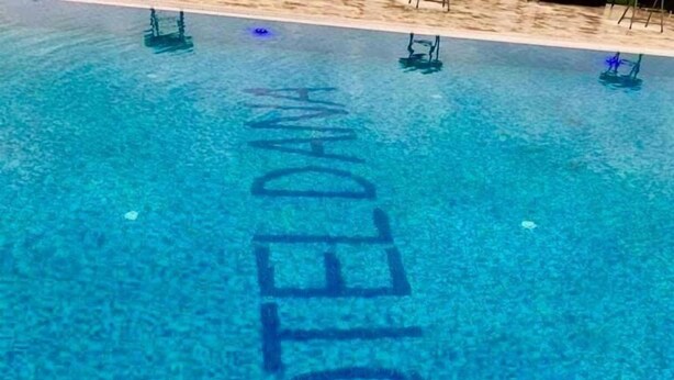 En klar, blå pool med ordet 'HOTEL' skrevet i midten.