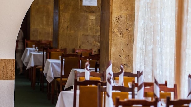 A restaurant with tables set for dining, wooden chairs, and hanging pendant lights. - Hotel Mures (Sânmartin)