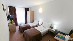 A hotel room with two single beds, a TV, a desk with a lamp, and a small table with a tissue box. - Hotel Mures (Sânmartin)