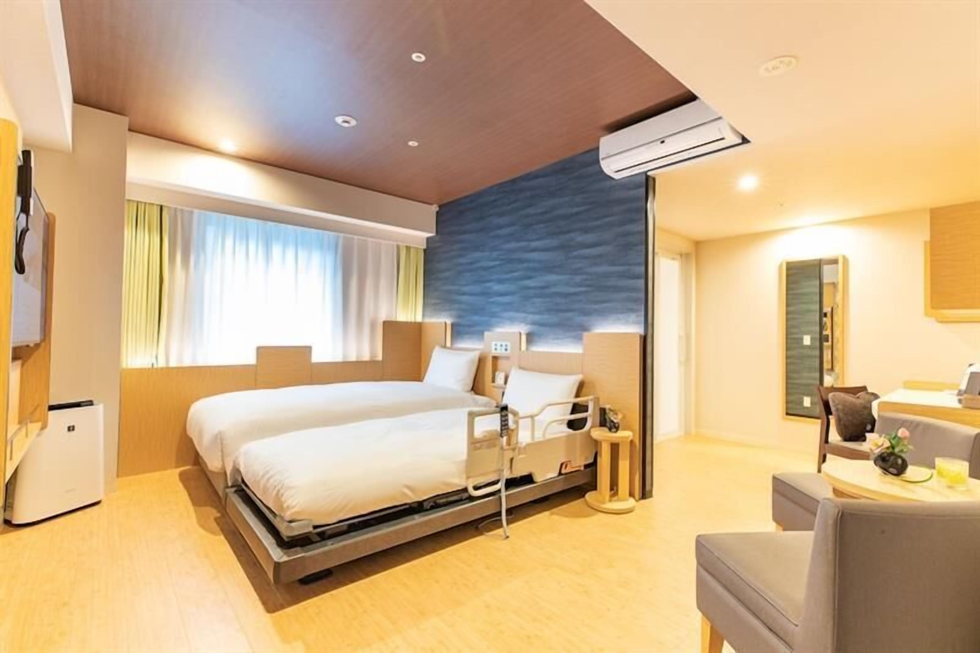 Une chambre d’hôtel moderne équipée d’un lit, d’une table de chevet, d’une chaise et d’un bureau avec une lampe.