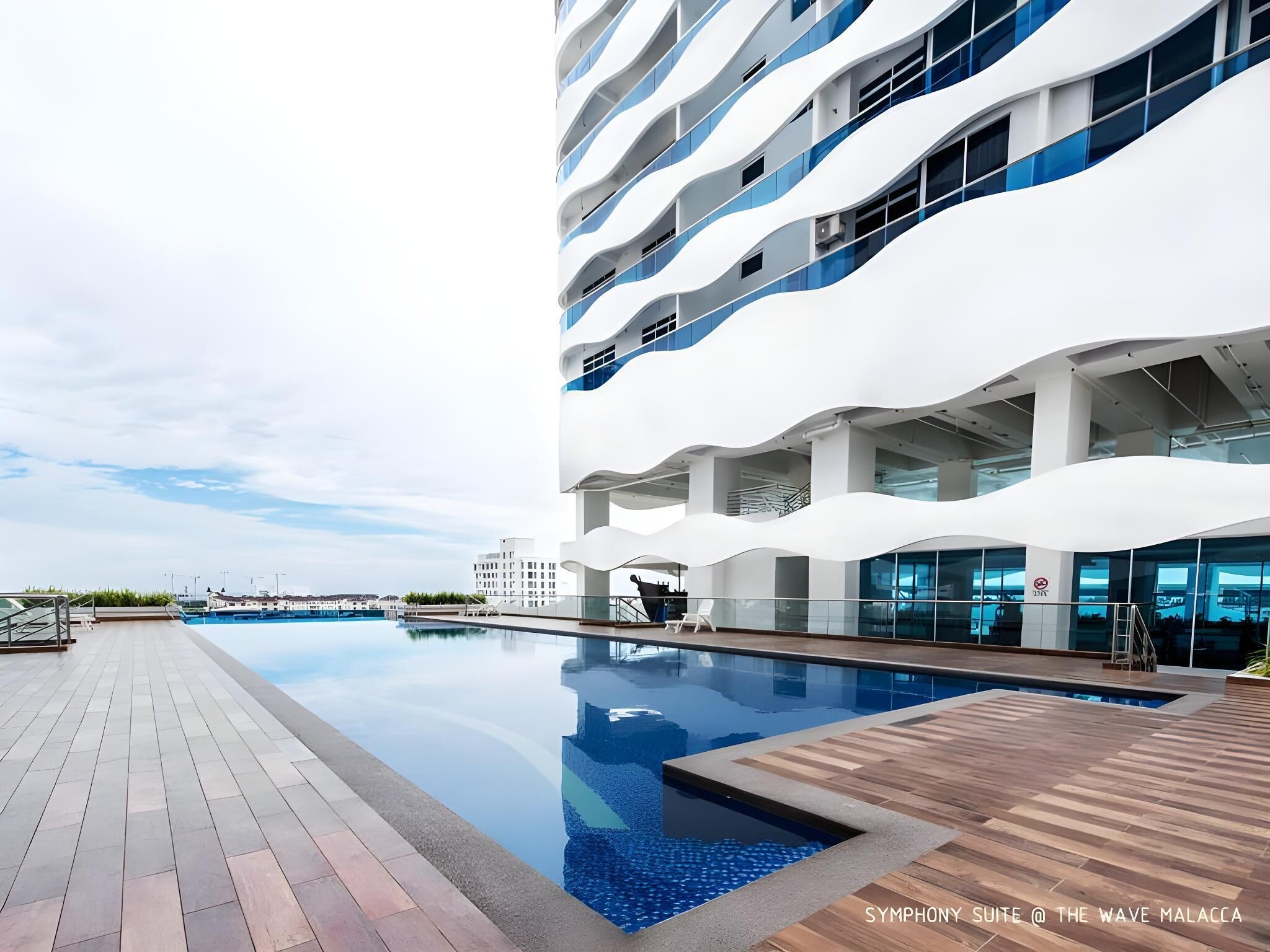A modern building with a pool and a wooden deck.