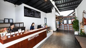 A reception desk with a digital screen displaying service times and a woman working behind it.