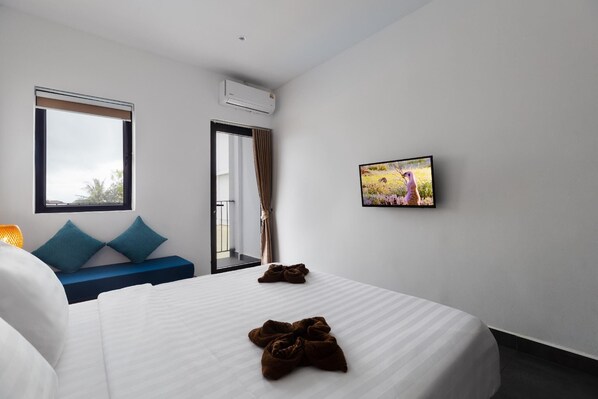 A hotel room with a bed, a blue sofa, a TV, and a window with curtains. - Onederz Sihanoukville (Sihanoukville)