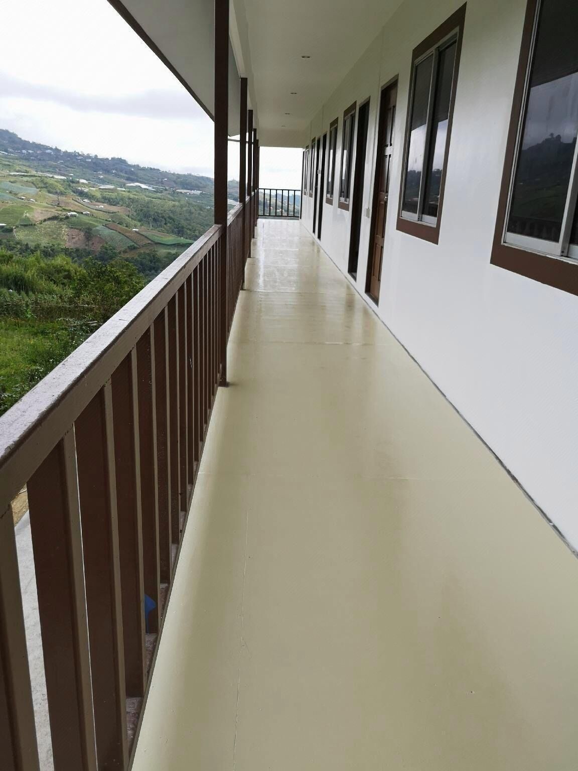 Um corredor longo com varanda com vista para uma paisagem verdejante.