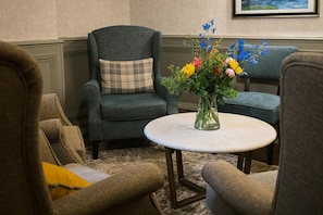 A room with two armchairs, a small round table with a vase of flowers, and a framed picture on the wall. - Grand Hotel Tralee (Tralee)