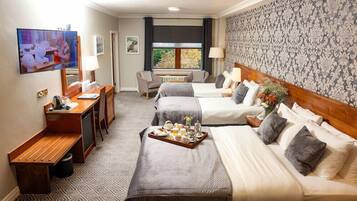 A hotel room with two beds, a desk, a TV, and a window with a view.