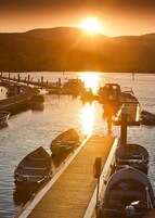 Un puerto deportivo con barcos amarrados a muelles de madera al atardecer.