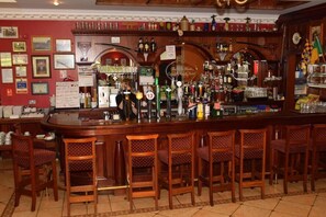 Eine Bar mit Holzkuben, einer Theke mit verschiedenen Flaschen und gerahmten Bildern an der Wand.