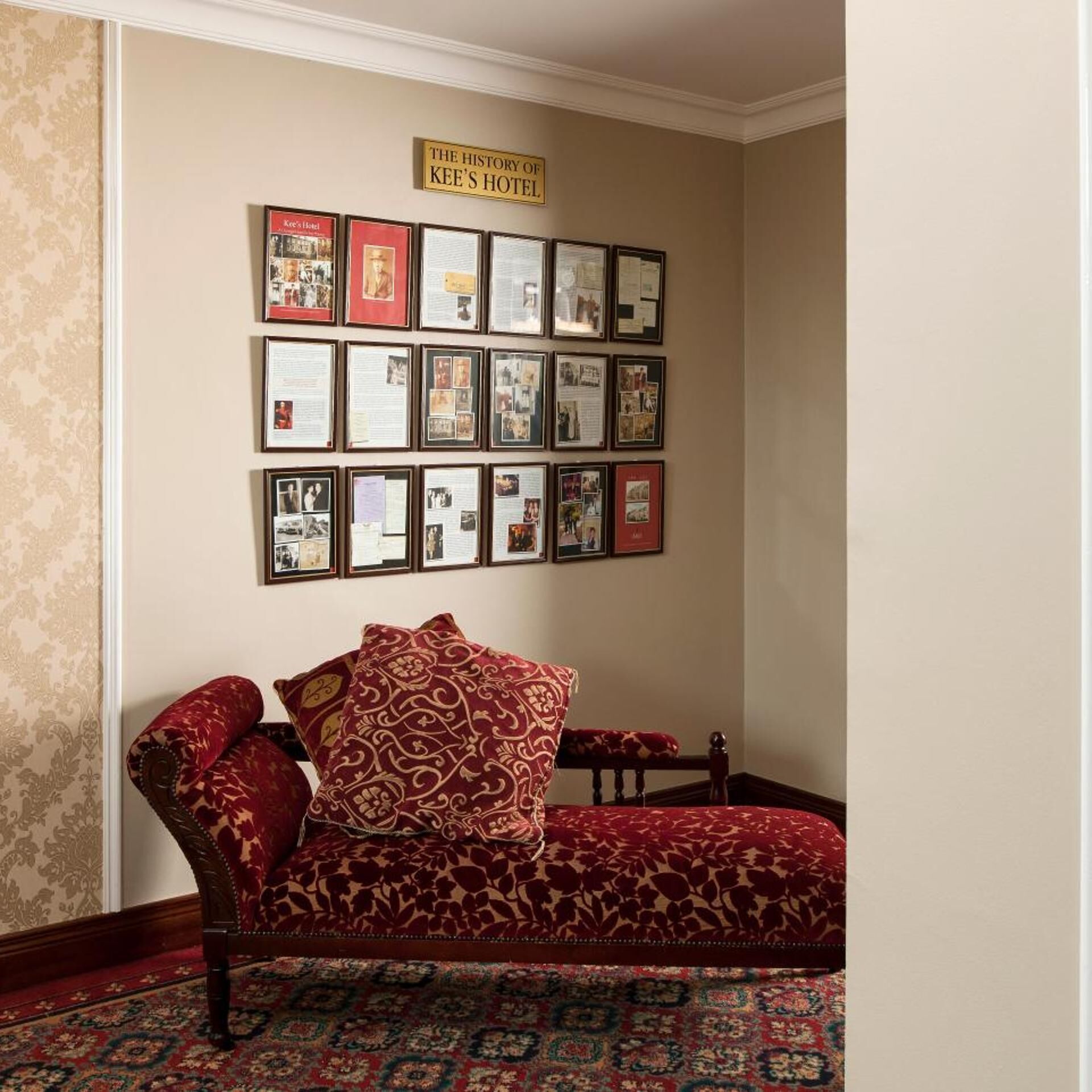 Ein Eckzimmer mit einer Couch, einer Wanddekoration aus Fotos und einem Teppich.