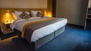 Et moderne hotelværelse med en stor seng, et træhovedgærde og et indbygget klædeskab.