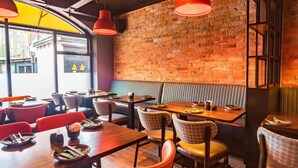 En restaurantindretning med murstensvægge, træborde og orange stole.