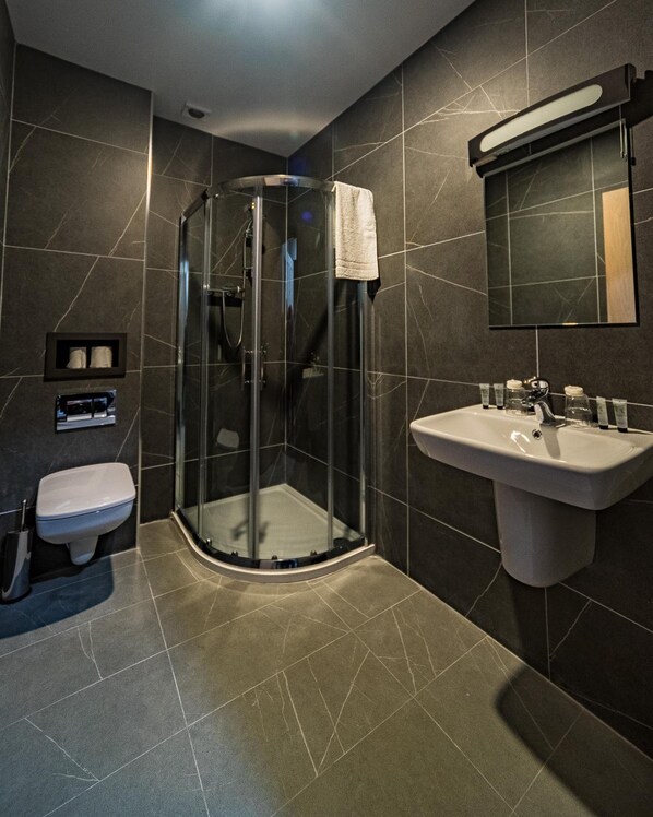 A modern bathroom with a glass-enclosed shower, a white sink, and a toilet.
