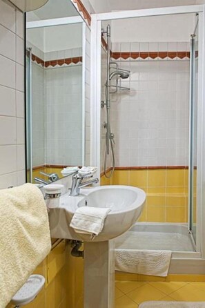 Un baño con lavamanos, espejo y ducha.