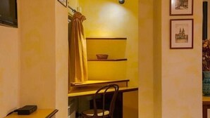 A compact hotel room with a small desk, a chair, a bed, and a television on the wall. - Residence Tynska (Prague)