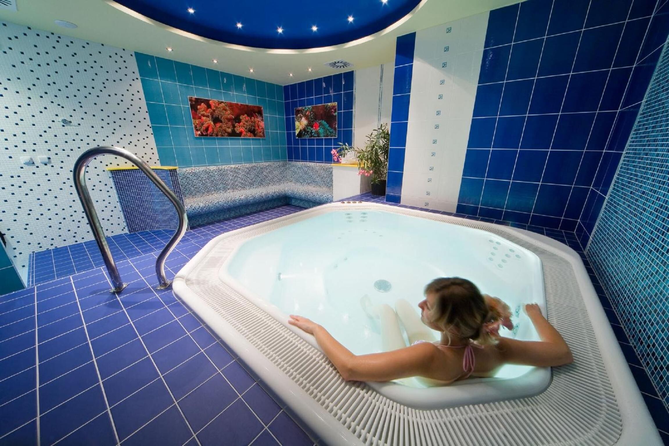 A spa area with a hot tub, a seating area, and a wall with a floral mural.