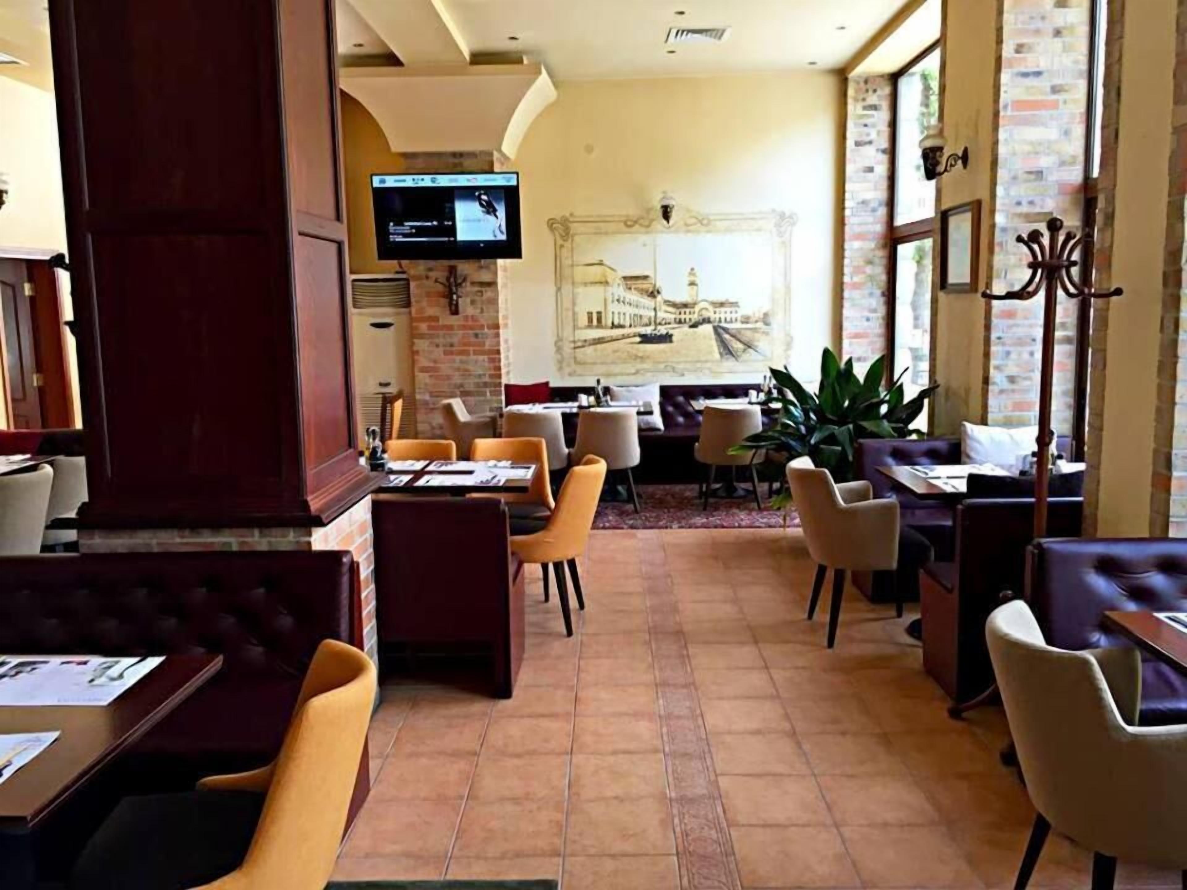 A restaurant with a brick wall, a mounted TV, and several tables and chairs.
