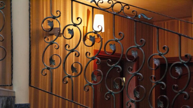 A staircase with ornate metal railings and wooden paneling. - Chipilakoff (Burgas)