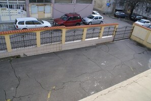 Un área de estacionamiento con una cerca amarilla y un coche rojo estacionado en el centro.