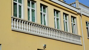 A yellow building with white-framed windows and a balcony with balustrades. - Chipilakoff (Burgas)
