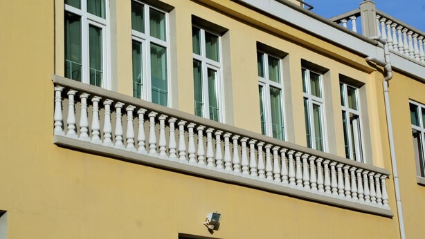 A yellow building with white-framed windows and a balcony with balustrades. - Chipilakoff (Burgas)
