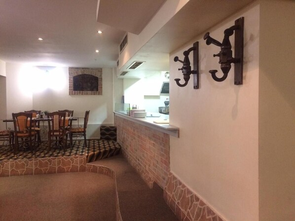 A dining area with a brick wall, a counter with kitchen items, and a seating arrangement with chairs and a table. - Chipilakoff (Burgas)