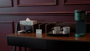 A wooden table with a tray holding a Keurig coffee maker, a tissue box, and a sign. - The Green Escape Suite (Mexico City)