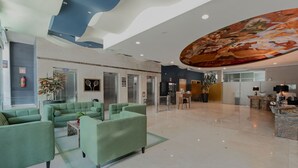 A spacious lobby with green sofas, a marble coffee table, and a large ceiling mural. - The Green Escape Suite (Mexico City)