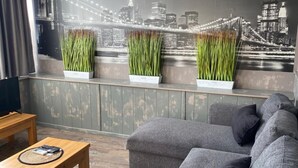 A living room with a sofa, a coffee table, and a mural of a city skyline. - City Hotel (Veliko Tarnovo)