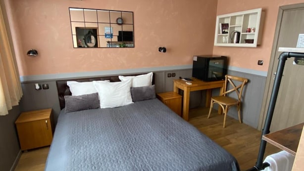 A hotel room with a large bed, a desk with a chair, a television, and a wardrobe. - City Hotel (Veliko Tarnovo)