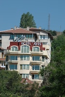 Um hotel de vários andares com uma placa bem visível com a inscrição "HOTEL AVIS".