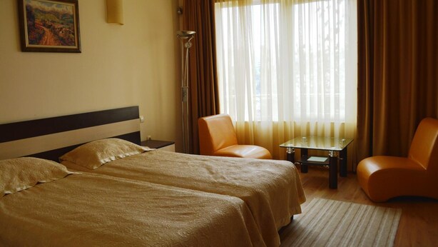 Une chambre d’hôtel avec deux lits, une chaise, une petite table et un tableau au mur.