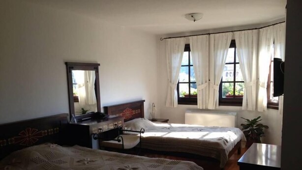 A bedroom with two beds, a desk, a chair, a mirror, and a window with curtains. - Gurko (Veliko Tarnovo)