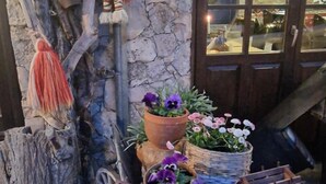 A rustic outdoor setting with a stone wall, a wooden bench, and a decorative figure. - Gurko (Veliko Tarnovo)