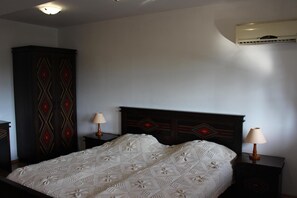 A bedroom with a bed, two bedside tables, an air conditioning unit, and a wardrobe. - Gurko (Veliko Tarnovo)