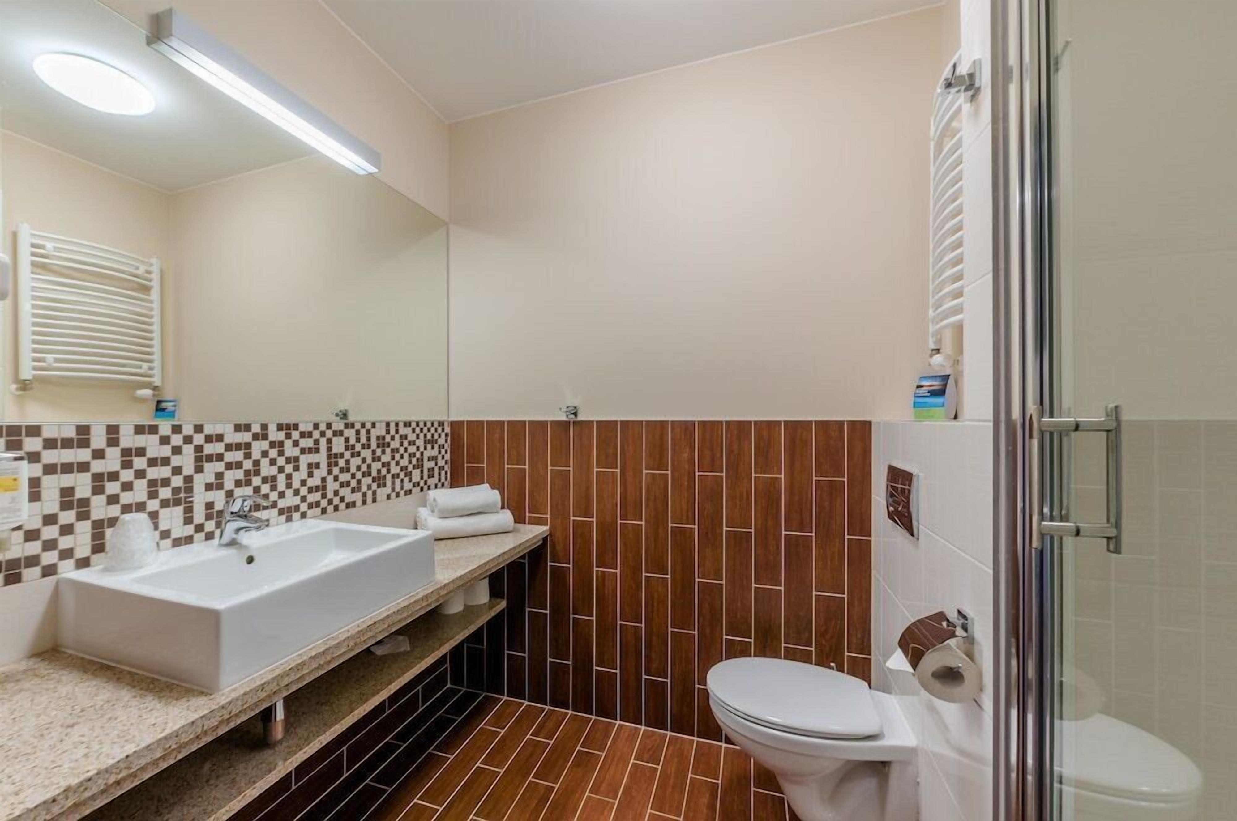 A bathroom with a white sink, a toilet, and a shower area.