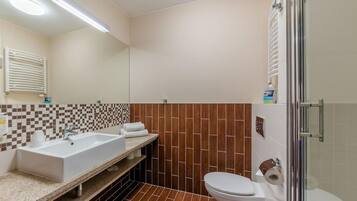 A bathroom with a white sink, a toilet, and a shower area.