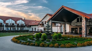 A hotel with a covered outdoor area, multiple balconies, and a landscaped garden. - Hotel Mikolajki Resort By Desilva (Mikolajki)