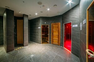 Un baño moderno con baldosas oscuras, zona de ducha y tocador con iluminación roja.