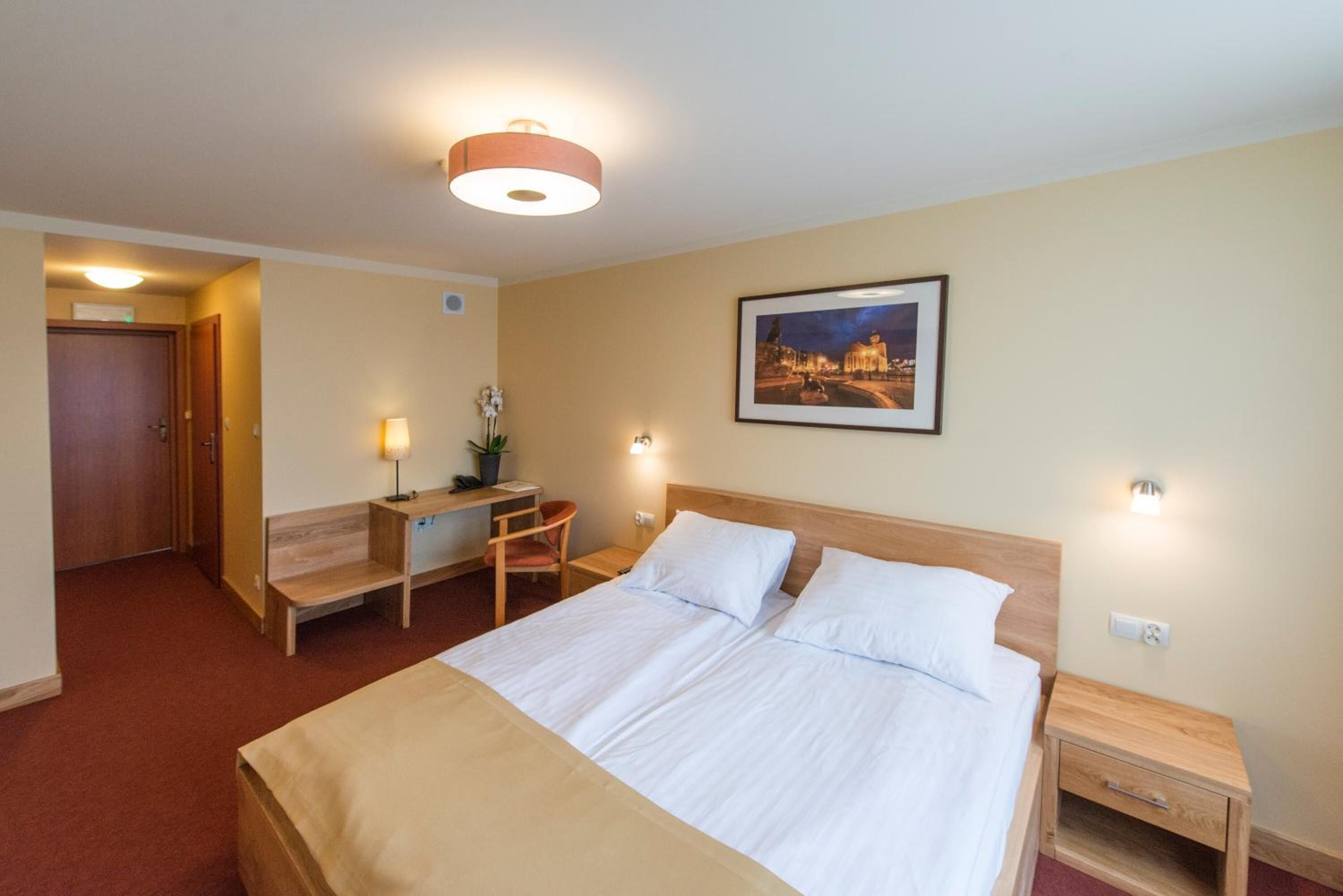 Ein Hotelzimmer mit Bett, Nachttischen, Schreibtisch und Stuhl.