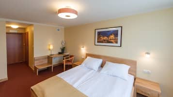Ein Hotelzimmer mit Bett, Nachttischen, Schreibtisch und Stuhl.