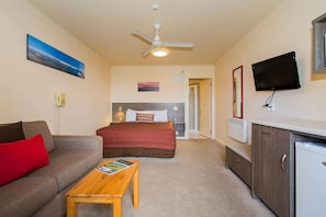 A hotel room with a bed, a sofa, a coffee table, a TV, and a kitchenette. - Lake Tekapo Scenic Resort (Lake Tekapo)