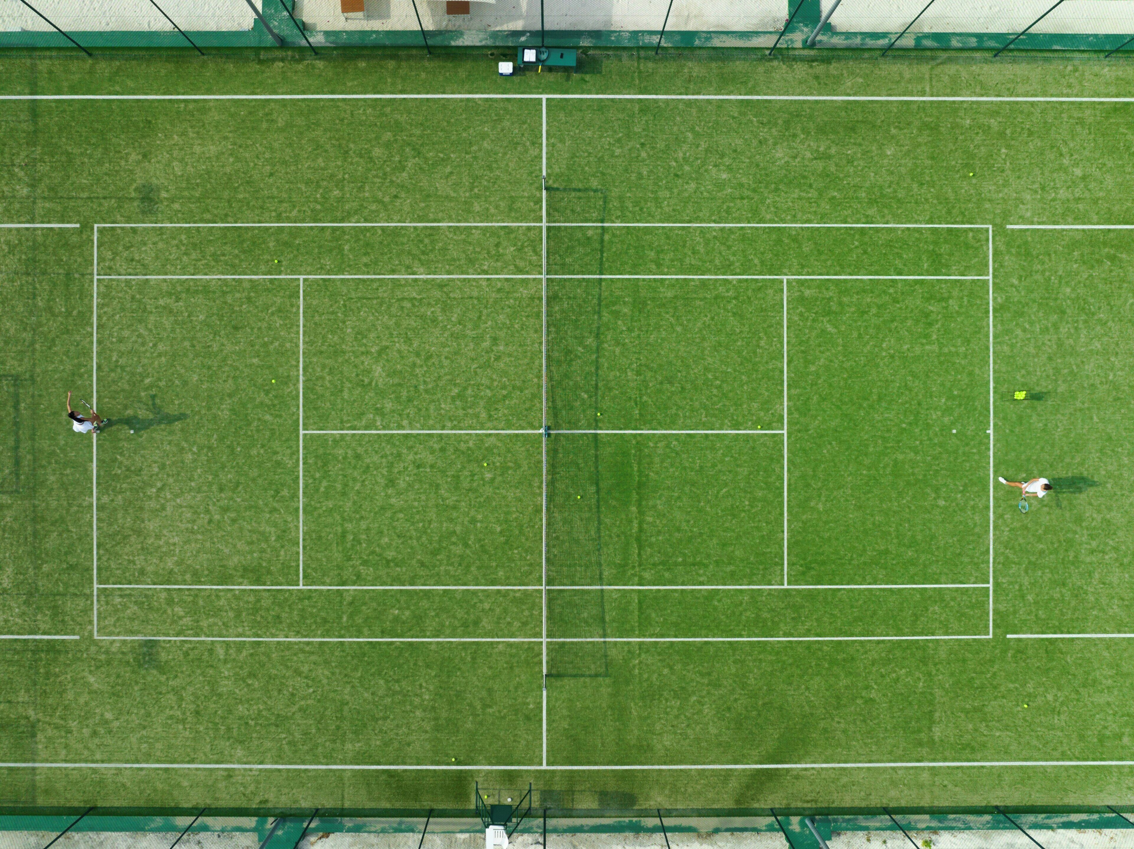 A tennis court with a net, boundary lines, and two players.