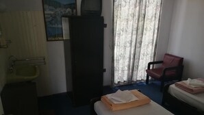 A hotel room with a bed, a chair, a sink, and a large window with curtains. - Miramare (Naousa)