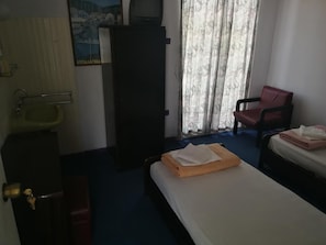 A hotel room with a bed, a chair, a sink, and a large window with curtains. - Driades Hotel (Naousa)