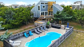 A residential property with a swimming pool, deck chairs, and a wooden deck. - 7221 - Wind & Waves Bungalow - Salvo Beach Bungalow w/ Pool & Hot Tub (Salvo)