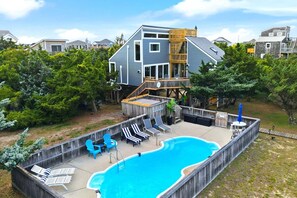 Ein Wohnhaus mit Schwimmbad, Liegestühlen und einer Holzterrasse.