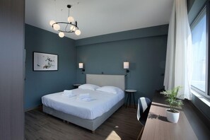 A modern hotel room with a large bed, bedside tables, a potted plant, and a window with curtains. - Athens 21 Hotel (Athens)